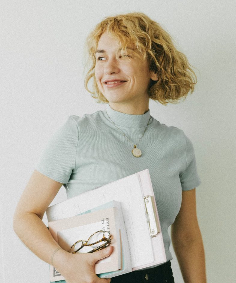 Alice Antonínová, smiling, holding a folder and glasses